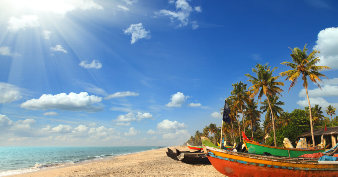 Fishing boats resting on a tropical Goa coastline under bright blue skies