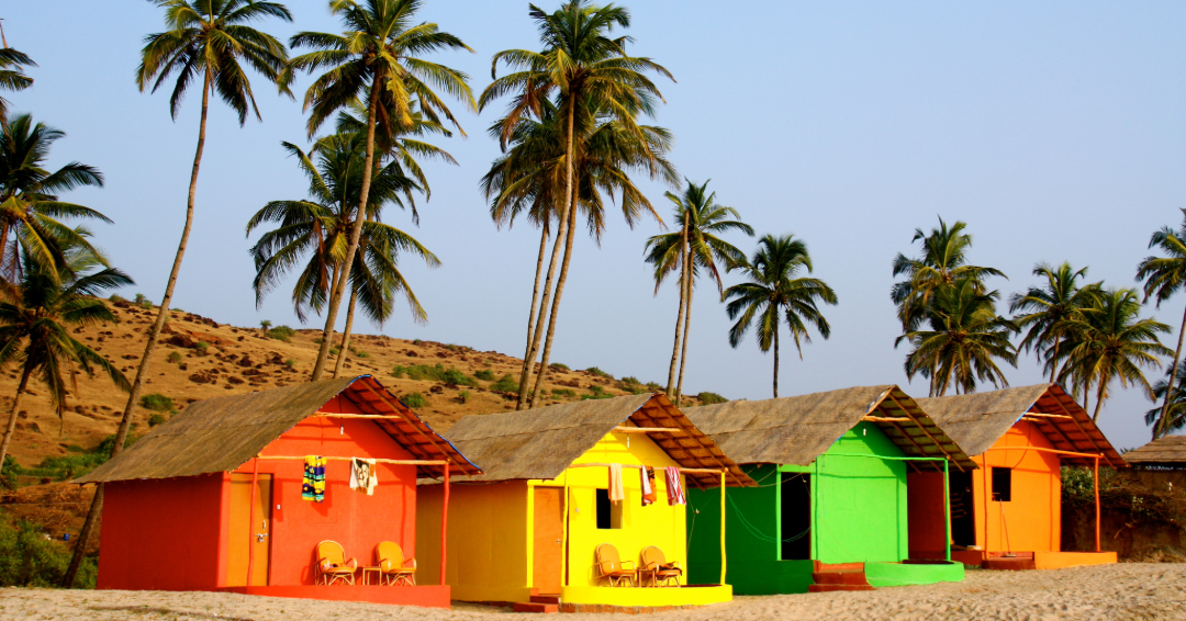 Bright beach huts and palm trees on a sunny Goa shore